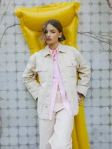 Chaqueta de algodón color arena, con cuello extendido, cierre con botones y cinturón para atar en la cintura.