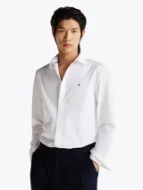 Camisa blanca de popelín de puro algodón con Flex Technology, cuello inglés, puños redondeados con botones y logo de Tommy Hilfiger bordado en el pecho.