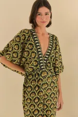 Mono largo con estampado geométrico en tonos negro, verde y dorado. Escote en V pronunciado con bordados en los bordes y mangas amplias.