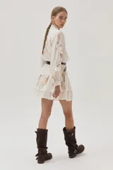 Blusa blanca de viscosa con cuello mao, cierre frontal con botones, mangas largas abullonadas con volados y bordados florales.