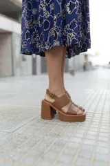 Sandalias de plataforma color marrón con textura símil piel de cocodrilo, con tres tiras anchas sobre el empeine, hebilla lateral y tacón ancho.