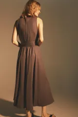 Vestido midi marrón sin mangas, con cuello solapa, escote en pico, cierre frontal con botones y cinturón de la misma tela con hebilla metálica.