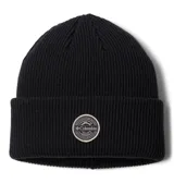 Gorro tipo beanie color negro, confeccionado en tejido de punto acrílico acanalado. Presenta un diseño con puño doblado y un parche circular bordado de la marca Columbia en la parte frontal.