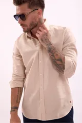 Camisa de manga larga color beige claro, de corte clásico y confeccionada en tejido texturizado.