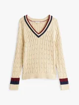 Sweater color crema de punto de cable con cuello en V con borde a rayas azul marino, rojo y blanco.