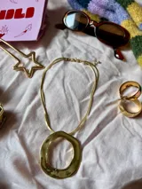 Collar dorado con cadena doble y dije circular irregular.