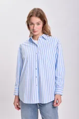 Camisa celeste con rayas verticales blancas, de corte oversize y manga larga.