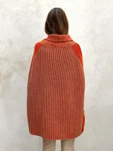 Poncho marrón de tejido de punto con cuello alto y diseño asimétrico.