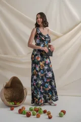 Vestido largo de satén de seda negro con estampado de flores de colores. Tiene escote irregular drapeado, un bretel ancho y otro fino con manga caída.