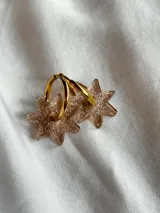 Par de aros dorados con forma de estrella negra.