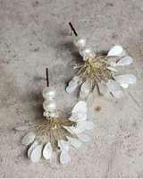 Par de aros colgantes con perlas blancas, alambre dorado y pétalos blancos.