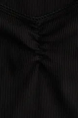 Remera corta negra de punto suave, corte ajustado, con costura fruncida en el centro del busto y escote corazón pronunciado con ribete de picot.