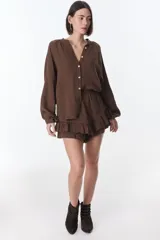 Camisa beige de manga larga con botones y detalles de encaje.