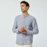 Camisa celeste de lino con cuello mao, manga larga con puños abotonados, cierre frontal con botones y bolsillo de parche en el pecho.
