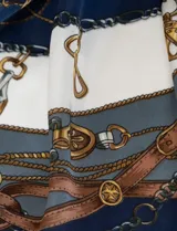 Pañuelo cuadrado de satén con estampado de cadenas doradas y detalles en rosa y blanco.