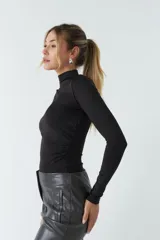 Body negro de poliéster y spandex, con cuello alto tipo polera, mangas largas y frunces laterales.
