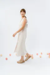 Vestido midi de lino en color verde seco, con escote en V, diseño sin mangas y cierre frontal con botones de madera. Presenta un corte recto y fluido con una abertura frontal en el bajo.