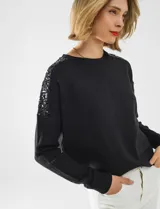 Buzo de tejido de punto color negro, con cuello redondo y mangas largas. Apliques de lentejuelas en los hombros. Marca Q2.