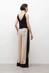 Pantalón ancho de lino color beige con paneles laterales negros y tajos en el ruedo.