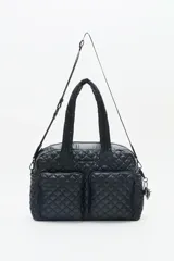 Bolso negro tipo tote bag, confeccionado en nylon matelassé con diseño acolchado en forma de rombos. Tiene doble asa corta y correa larga desmontable. Incluye llavero de corazón y dijes desmontables, y compartimento interior para notebook.