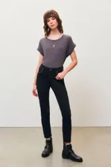 Pantalón jean negro de corte slim con detalles de tachas plateadas en los bolsillos delanteros y en el ruedo.