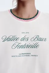 Camiseta blanca de algodón con cuello redondo y detalle de tricot a contraste en azul marino. Estampado frontal con texto "Estate sulla Costiera Amalfitana" en azul marino.