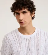 Remera blanca de algodón con textura de punto en líneas verticales, cuello redondo y mangas cortas.