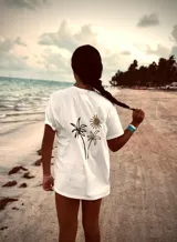 Remera blanca con estampado de palmeras y sol en la espalda.