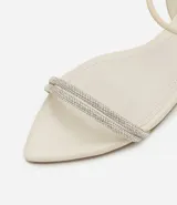 Sandalia plana color crema con punta de hoja, tira elástica en el talón y tiras dobles cubiertas de strass en la parte superior.