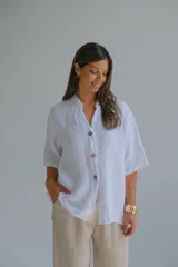 Camisa blanca de lino con cuello mao, manga corta y cierre frontal con botones.