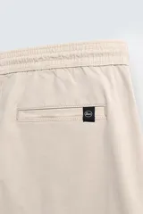 Pantalón jogger negro de corte slim fit, confeccionado en tejido de algodón con cintura elástica ajustable con cordón, bolsillos frontales y traseros de vivo, y bajo con puño elástico.
