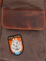 Mochila de lona color marrón con detalles en cuero color marrón oscuro. Tiene un compartimento principal con cierre de cremallera y solapa con broche imantado, bolsillo acolchado interior para laptop de 15", bolsillo interior con cierre, un bolsillo frontal con cierre, bolsillos laterales, pasador en la parte de atrás para maleta, bolsillo trasero con cierre cremallera, correas ajustables y forro interior con diseño Star Wars.
