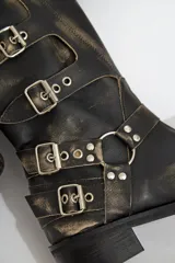 Botas de cuero gastado color marrón con hebillas y apliques de metal de caña alta.