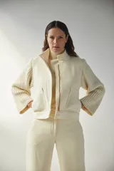Campera con cuello alto y mangas de tejido de punto, con cierre frontal de botones ocultos y bolsillos de doble abertura.