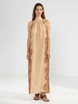 Vestido largo color naranja con estampado de flores rosas, corte recto, cuello halter y espalda descubierta.