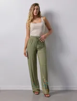 Pantalón verde oliva de rayón con cintura elastizada tipo smock y bordados florales en los bajos.