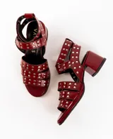 Sandalias de cuero color bordó con tres tiras horizontales sobre el empeine y pulsera al tobillo, ambas con apliques de tachas plateadas.