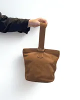 Cartera tipo tote bag de cuero color marrón, con manija corta y cierre superior.