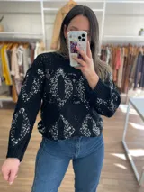 Sweater tejido negro con cuello redondo y mangas largas. Presenta un patrón de rombos con lentejuelas plateadas.