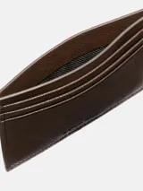 Tarjetero de piel granulada color marrón oscuro, con seis ranuras frontales para tarjetas y una ranura central. Presenta protección RFID y el logo de Calvin Klein grabado en la parte delantera.