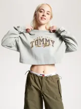 Buzo Tommy Jeans de corte cropped, color gris claro, con logo bordado en el frente.