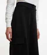 Pantalón largo negro de material sintético con cintura elástica, bolsillos laterales tipo cargo y abotonado delantero.