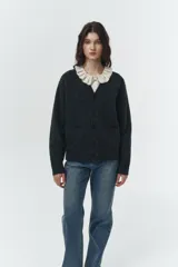 Cardigan de punto gris oscuro jaspeado, con cuello en V, cierre frontal de botones y dos bolsillos frontales tipo parche. Corte relajado y holgado.