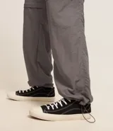 Pantalón paper touch color verde militar, con bolsillos laterales, cintura elástica y cordón de ajuste. Se convierte en bermuda gracias a un cierre a la altura de la rodilla.