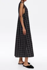 Vestido midi negro con estampado a cuadros blancos, corte recto, escote redondo y tirantes con lazos.