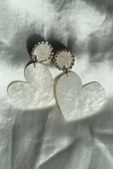 Aros colgantes con forma de corazón nacarado y base circular con strass plateados.