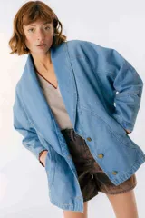 Chaqueta celeste de denim con cuello solapa, corte holgado y cierre frontal con botones dorados.
