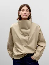 Camisa beige de algodón con cuello chimenea y cierre lateral con cuatro broches a presión. Manga japonesa con corte en la sisa en la espalda y puño con abertura y broche.