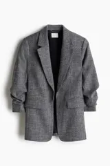 Blazer gris con textura, corte entallado, solapas de muesca, mangas tres cuartos fruncidas y bolsillos delanteros con solapa.