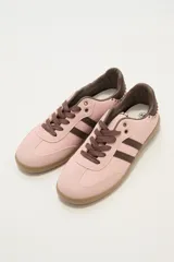 Zapatillas deportivas color rosa con detalles en marrón, cordones marrones y suela color caramelo.